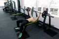 Young muscular Caucasian man lifting barbell on the bench in the gym. Royalty Free Stock Photo