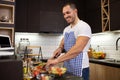 Young muscular guy with apron preparing to cook a delicious meal from confinements of his kitchen, cooking from home Royalty Free Stock Photo