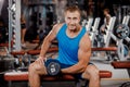 A young muscular guy does hard exercises with dumbbells for the rear deltas of the shoulders on a training bench in the gym Royalty Free Stock Photo