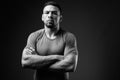 Young muscular Hispanic man against black background