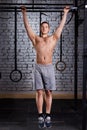 Young muscular male doing exercises on horizontal bar in a gym club against brick wall. Royalty Free Stock Photo