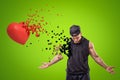 Young muscular man in black sport clothing and red heart shattering into small pieces on green background