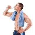 Young muscular man with blue towel over neck, drinking water, isolated on white