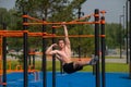 Young muscular man hanging by one hand on a horizontal bar outdoors. Royalty Free Stock Photo