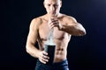 Young muscular man pours protein nutrition supplement into a black plastic shaker