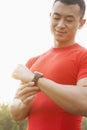 Young muscular man with red shirt looking down and checking his watch, outdoors in Beijing Royalty Free Stock Photo