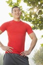 Young muscular man in red shirt standing and smiling, outdoors in a park in Beijing Royalty Free Stock Photo