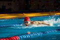 Young muscular man showing competitive spirit, swimmer in cap and goggles training, swimming in pool, preparing for Royalty Free Stock Photo