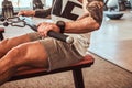 Young muscular man with tattoes is doing exercises on the rowing machine