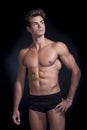 Young muscular man in underwear with a black background