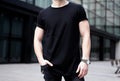 Young muscular man wearing black tshirt and jeans posing in center of modern city. Blurred background. Hotizontal mockup Royalty Free Stock Photo