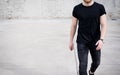 Young muscular man wearing black tshirt and jeans walking on the urban district. Blurred background. Hotizontal mockup.