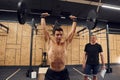 Young muscular man lifting barbell in the gym. Trainer standing and watching Royalty Free Stock Photo