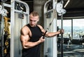 Young muscular sweaty fit man doing triceps workout training in the gym on cable machine for big arms muscles real people exercisi Royalty Free Stock Photo