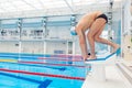Young muscular swimmer in low position on starting block a swimming pool Royalty Free Stock Photo