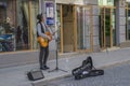 Young musician boy playing guitar and singing on street