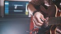 Young musician composes and records soundtrack playing the guitar using computer and keyboard Royalty Free Stock Photo