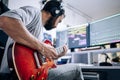 Young musician playing electric guitar with headphones at home studio Royalty Free Stock Photo