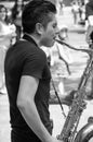 Young musician playing the sax in the middle of thr street as a way to earn income