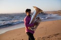 Young musician playing the tuba on the sea coast. Hobby. Royalty Free Stock Photo