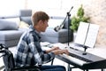 Young musician in wheelchair playing synthesizer at home