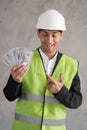 Young muslim builder man engineer wearing safety helmet holding money dollars as payment over background, a foreman