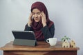 A young Muslim business woman feel stressed frown, so put her hands on the head in hijab dress and suit using laptop