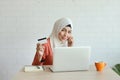 Young muslim businesswoman shopping and online payment by using notebook, cell phone and credit card with coffee cup on wood desk Royalty Free Stock Photo