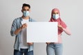 Young muslim couple in protective medical masks holding white blank placard Royalty Free Stock Photo