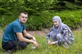 Young Muslim Couple Squatting On Grass And Looking To The Camera