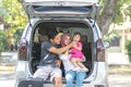 Young muslim family , transport, leisure, road trip and people concept - happy man, woman and little girl sitting on trunk of Royalty Free Stock Photo