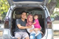 Young muslim family , transport, leisure, road trip and people concept - happy man, woman and little girl sitting on trunk of Royalty Free Stock Photo