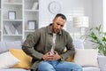 A young Muslim man grimaced in pain and holds his hands to the side of his stomach, suffering from appendicitis Royalty Free Stock Photo