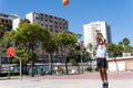 Young muslim man playing street basketball in a city court, throwing ball, training and sport concep