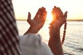 Young Muslim man praying near river at sunset Royalty Free Stock Photo