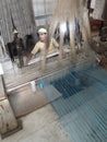 Young muslim man runs a loom to weave silk brocade