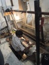 Young muslim man runs a loom to weave silk brocade