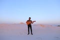 Handsome male Arab playing guitar standing in middle of bottomle