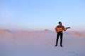 Handsome male Arab playing guitar standing in middle of bottomle