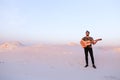 Handsome male Arab playing guitar standing in middle of bottomle