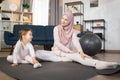 Young muslim mother in hijab showing her little daughter legs stretching exercises. Royalty Free Stock Photo