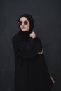 Young muslim in traditional clothes or abaya and sunglasses posing in front of black chalkboard
