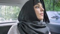 Young muslim woman in hijab is looking out for location in rainy window in car, transport concept, weather concept