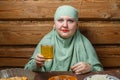 A young Muslim woman in a light khimar drinks uzwar at the table during Iftar Ramadan