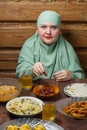 A young Muslim woman in a light khimar at the table eats a date during Iftar Ramadan