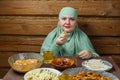 A young Muslim woman in a light khimar at the table eats lamb during Iftar Ramadan