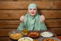 A young Muslim woman in a light khimar at the table says bismi llah before Iftar Ramadan Royalty Free Stock Photo