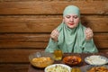 A young Muslim woman in a light khimar at the table says bismi llah before Iftar Ramadan Royalty Free Stock Photo