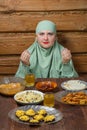 A young Muslim woman in a light khimar at the table says bismi llah during Ramadan iftar Royalty Free Stock Photo