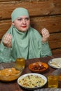 A young Muslim woman in a light khimar at the table says bismi llah during Ramadan iftar Royalty Free Stock Photo